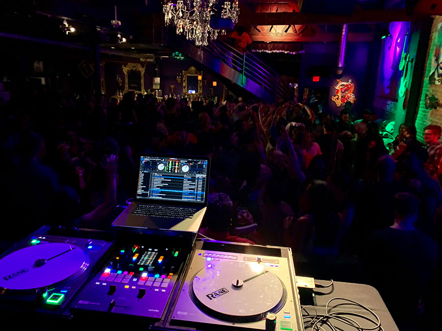 Professional DJ booth with Pioneer mixer at a packed Chicago nightclub
